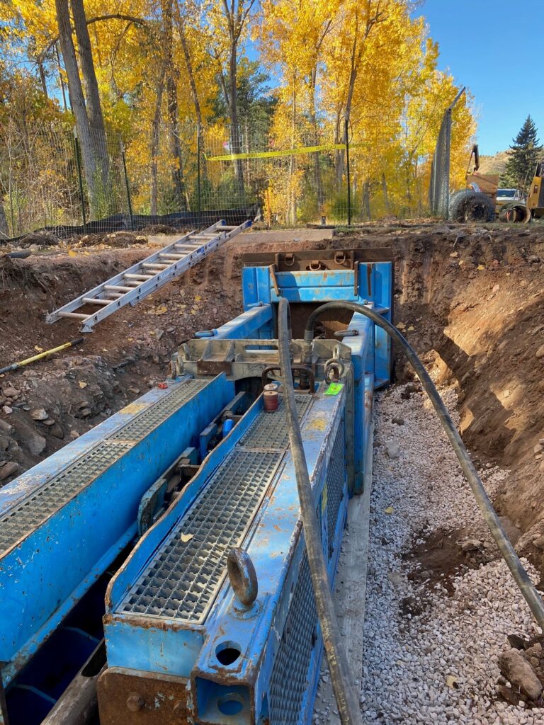 A Mainline Contracting sewer work site with heavy machinery in a ditch